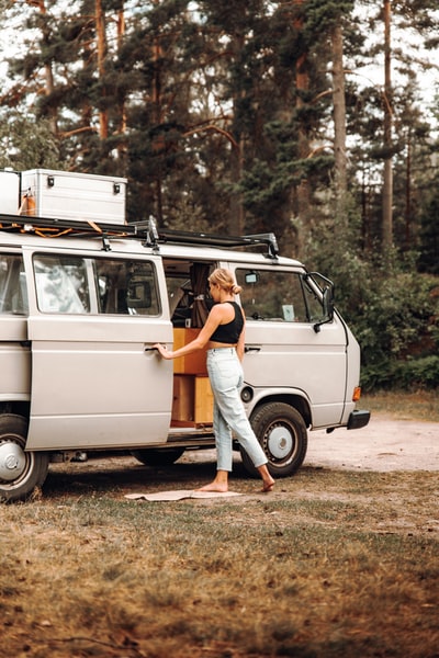 Wearing orange shirt and grey trousers woman sitting on a white van
